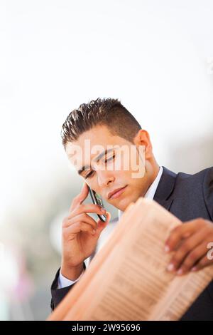 Geschäftsmann, gelegen in einer Bank anrufen auf zellulärer und seine Zeitung lesen Stockfoto