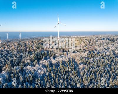 Windturbinen ragen über einem schneebedeckten Nadelwald unter blauem Himmel, aus der Vogelperspektive, Schwarzwald Dobel, Deutschland Stockfoto