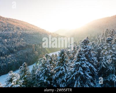 Die untergehende Sonne hinter einem schneebedeckten Bergwald, Dobel, Luftaufnahme, Schwarzwald, Deutschland Stockfoto
