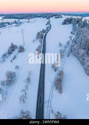 Eine leere Straße führt durch eine winterliche Landschaft in der Dämmerung, Luftsicht, Calw-Stammheim, Schwarzwald, Deutschland Stockfoto