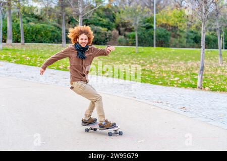 Rothaarige Lockenhaare junger Mann, der im Herbst in einem Park Schlittschuhlaufen will Stockfoto