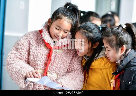 (231224) -- ANSHUN, 24. Dezember 2023 (Xinhua) -- Ji Xue (1. L) zeigt ihre englische Komposition an Schulkameraden im Bezirk Xixiu der Stadt Anshun, südwestchinesische Provinz Guizhou, 22. Dezember 2023. Vor fünf Jahren begannen die sechsjährige Ji Xue und ihre Familie aus der ethnischen Gruppe der Miao ein neues Leben. Dank der Bemühungen zur Armutsbekämpfung wurden sie in ein neues Zuhause aus unwirtlichen Bergregionen und abgelegenen Gebieten umgesiedelt. In den letzten fünf Jahren sind die Unterstützungseinrichtungen in der Umsiedlungsgemeinschaft, in der Ji heute lebt, immer besser geworden. Es dauerte mehr als zwei Stunden, bis Ji zu Fuß nach sch kam Stockfoto