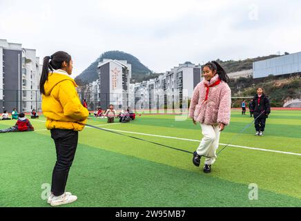 (231224) -- ANSHUN, 24. Dezember 2023 (Xinhua) -- Ji Xue (C) spielt mit Klassenkameraden in der Schule im Bezirk Xixiu der Stadt Anshun, südwestchinesische Provinz Guizhou, 22. Dezember 2023. Vor fünf Jahren begannen die sechsjährige Ji Xue und ihre Familie aus der ethnischen Gruppe der Miao ein neues Leben. Dank der Bemühungen zur Armutsbekämpfung wurden sie in ein neues Zuhause aus unwirtlichen Bergregionen und abgelegenen Gebieten umgesiedelt. In den letzten fünf Jahren sind die Unterstützungseinrichtungen in der Umsiedlungsgemeinschaft, in der Ji heute lebt, immer besser geworden. Es dauerte mehr als zwei Stunden, bis Ji zur Schule ging, auf einer bergigen Straße. Stockfoto