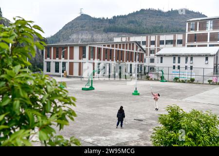 (231224) -- ANSHUN, 24. Dezember 2023 (Xinhua) -- Ji Xue (R) spielt Badminton mit einem Lehrer an der Schule im Bezirk Xixiu der Stadt Anshun, südwestchinesische Provinz Guizhou, 22. Dezember 2023. Vor fünf Jahren begannen die sechsjährige Ji Xue und ihre Familie aus der ethnischen Gruppe der Miao ein neues Leben. Dank der Bemühungen zur Armutsbekämpfung wurden sie in ein neues Zuhause aus unwirtlichen Bergregionen und abgelegenen Gebieten umgesiedelt. In den letzten fünf Jahren sind die Unterstützungseinrichtungen in der Umsiedlungsgemeinschaft, in der Ji heute lebt, immer besser geworden. Es dauerte mehr als zwei Stunden, bis Ji mit dem Berg zur Schule kam Stockfoto