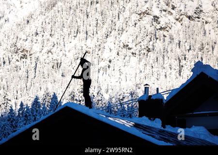 Grainau, Deutschland. Dezember 2023. Ein Mann entfernt Schnee vom Dach eines Hauses. Quelle: Matthias Balk/dpa/Alamy Live News Stockfoto