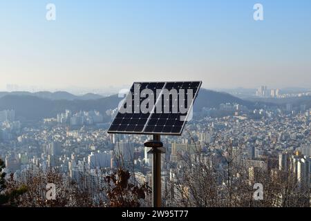 Zwei Sonnenkollektoren auf einem Edelstahlmast bei Sonnenuntergang mit Eunpyeong District, Seoul im Hintergrund Stockfoto