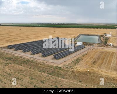 Luftaufnahme einer Solarpaneelanlage zur Erzeugung sauberer elektrischer Energie in der Industrie neben einem landwirtschaftlichen Bewässerungsteich. Drohnenaufnahmen Stockfoto