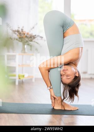 Erfahrene Mädchen-Fitness-Clublehrerin führt Uttanasana auf Stockfoto