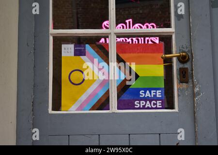 Eine LGBTQI+-Flagge hinter einem Fenster in einer Tür, die zu einem sicheren Raum führt, der vom stadtrat von Brügge organisiert wird Stockfoto