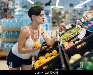 Frau wählt Pfirsiche im Supermarkt Stockfoto
