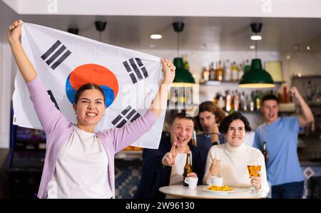 Eine Gruppe von glücklichen Freunden mit der Flagge von Südkorea, die den Sieg ihrer Lieblingsmannschaft in der Bierstube feiern Stockfoto