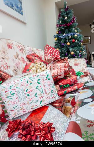 Weihnachtsgeschenke auf einem Sofa, eingewickelt in dekoratives festliches Geschenkpapier. Stockfoto