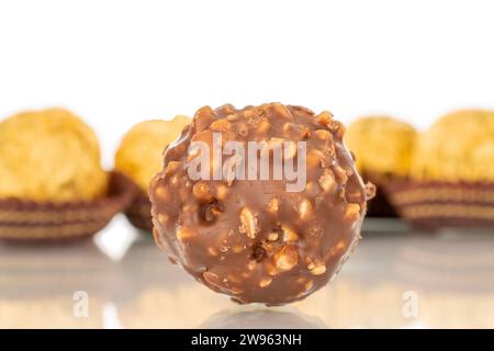 Mehrere Schokoladenbonbons mit Nüssen in einer Papierverpackung, Makro, isoliert auf weißem Hintergrund. Stockfoto