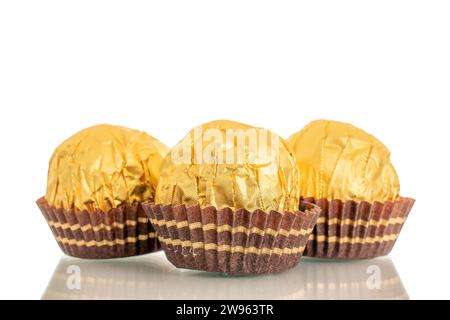 Drei Schokoladenbonbons mit einer Nuss in einer Papierverpackung, Makro, isoliert auf weißem Hintergrund. Stockfoto