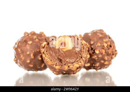 Eine Hälfte Schokoladenbonbons mit Nuss und zwei ganze Süßigkeiten, Makro, isoliert auf weißem Hintergrund. Stockfoto