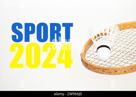 Badmintonschläger und Shuttlecock auf weißem Hintergrund und der Text Sport 2024 im gelb-blauen Licht der ukrainischen Flagge, Sport im neuen Jahr Stockfoto