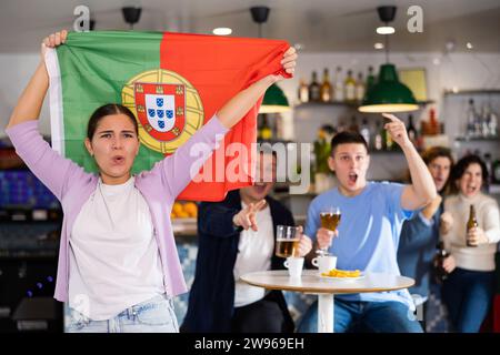 Fans mit der Flagge Portugals feiern den Sieg ihrer Lieblingsmannschaft in der Bierstube Stockfoto