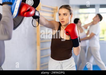 Junge Frau und erwachsener Mann, der Boxpunze im Studio trainiert. Stockfoto