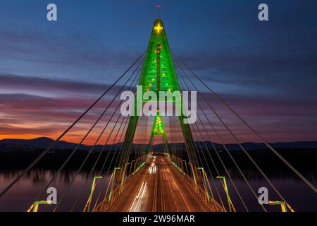 Aus nächster Nähe sehen Sie die beleuchtete Megyeri-Brücke in einer seltenen weihnachtsdekoration bei Sonnenuntergang. Stockfoto