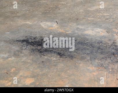 Schwarzer Ruß oder Ölpest aus dem Auspuffrohr des Autos fiel auf schmutzigen Zement- oder Betonboden in der alten Garage. Stockfoto