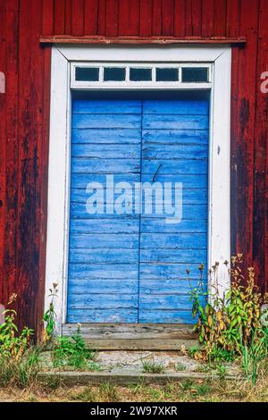 Blaue Tür in einem alten roten Holzhaus Stockfoto