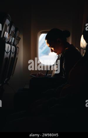 Eine weibliche Passagierin, die in einem Flugzeug in der Nähe des Fensters sitzt. Stockfoto