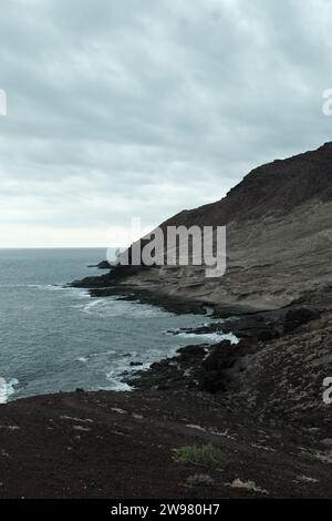 Eine ruhige Meereslandschaft mit einem Strand mit felsigen Formationen und üppigem grünem Gras, der sich vom Rand des Ozeans bis zum Sandstrand erstreckt Stockfoto