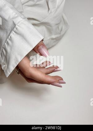 Eine Nahaufnahme eines Weibchens mit sorgfältig gepflegten pastellrosa Fingernägeln Stockfoto