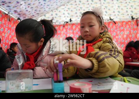 Jishishan, Chinas Provinz Gansu. Dezember 2023. Die Schüler besuchen eine psychologische Beratung in einem temporären Klassenzimmer in einem Zelt in der Gemeinde Liugou im Jishishan County, nordwestchinesische Provinz Gansu, 25. Dezember 2023. Grund- und Sekundarschulen in den von Erdbeben betroffenen Gebieten von Jishishan begannen am Montag nach einer Sicherheitsüberprüfung wieder den Unterricht aufzunehmen. Quelle: Chen Bin/Xinhua/Alamy Live News Stockfoto