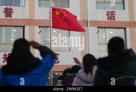 Jishishan, Chinas Provinz Gansu. Dezember 2023. Am 25. Dezember 2023 findet in einer Grundschule in der Gemeinde Liugou im Jishishan County in der nordwestlichen chinesischen Provinz Gansu eine Flaggenhahnungszeremonie statt. Grund- und Sekundarschulen in den von Erdbeben betroffenen Gebieten von Jishishan begannen am Montag nach einer Sicherheitsüberprüfung wieder den Unterricht aufzunehmen. Quelle: Chen Bin/Xinhua/Alamy Live News Stockfoto