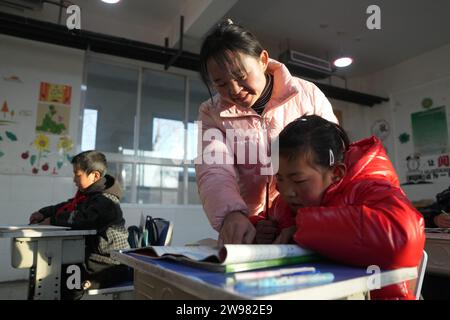 Jishishan, Chinas Provinz Gansu. Dezember 2023. Ein Lehrer unterrichtet einen Schüler an einer Grundschule in der Gemeinde Liugou im Jishishan County, nordwestchinesische Provinz Gansu, am 25. Dezember 2023. Grund- und Sekundarschulen in den von Erdbeben betroffenen Gebieten von Jishishan begannen am Montag nach einer Sicherheitsüberprüfung wieder den Unterricht aufzunehmen. Quelle: Chen Bin/Xinhua/Alamy Live News Stockfoto