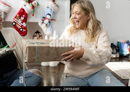 Frau, die ein weihnachtsgeschenk hält, lächelt und lacht Stockfoto