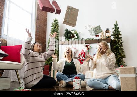 Frauen, die eingepackte weihnachtsgeschenke in die Luft werfen Stockfoto