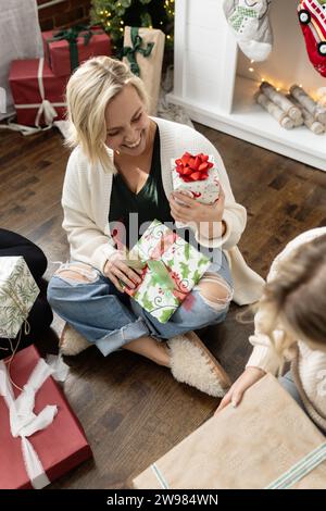 Frau lächelt und sieht sich ein verpacktes weihnachtsgeschenk an Stockfoto