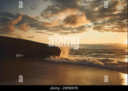 Wellenplätschern auf dem alten Bunker des 2. Weltkriegs an der dänischen Küste bei Sonnenuntergang. Hochwertige Fotos Stockfoto