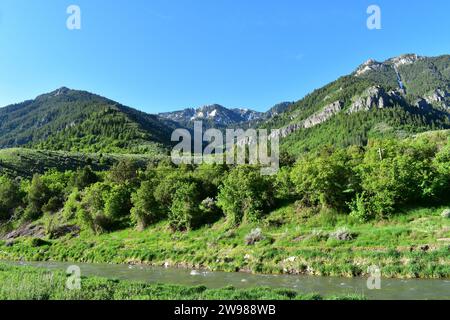 Malerischer Naturblick auf einen Wasserstrom, der durch die Landschaft fließt, mit den majestätischen Gipfeln der Rocky Mountains im Hintergrund von Utah Stockfoto