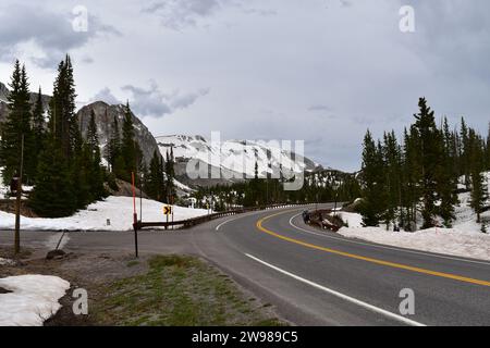 Die Straße 130 führt durch die schneebedeckte Berglandschaft des Medicine Bow-Routt National Forest Stockfoto