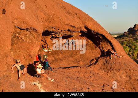 Leute sitzen auf dem roten Sandstein von Hole in the Rock und genießen den Sonnenuntergang Stockfoto