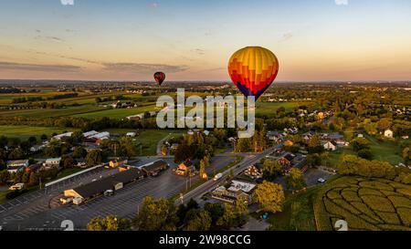 Ein Blick aus der Vogelperspektive auf zwei Heißluftballons, die bei Sonnenaufgang an einem sonnigen Sommermorgen starten und davonfliegen Stockfoto