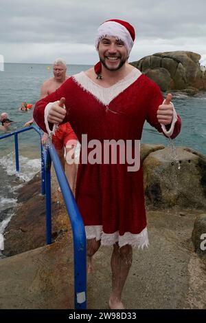 Schwimmer, die als weihnachtsmann gekleidet sind und am jährlichen Weihnachtstag teilnehmen, schwimmen am vierzig Fuß langen Badeplatz in Sandycove Dublin. Bilddatum: Mittwoch, 13. Dezember 2023. Stockfoto