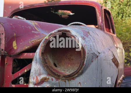 Ein verlassener klassischer rostrostiger Wagen, demontierter Scheinwerfer des Autos Stockfoto