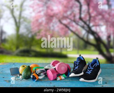 Sport und Fitness im Frühling und Sommer, flache Liege mit Sportgeräten, Wasserflasche, Dummeln, Maßband, Smartphone und Obst. Verschwommenes Frühjahrsfest Stockfoto