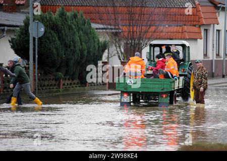 Windehausen, Deutschland. Dezember 2023. Ein Traktor fährt durch das überflutete Dorf Windehausen. Die Hochwassersituation in Nordthüringen ist weiterhin angespannt. Das Dorf Windehausen im Landkreis Nordhausen ist vom Wasser eingeschlossen und sollte ab Montagnachmittag vollständig evakuiert werden. Quelle: Stefan Rampfel/dpa/Alamy Live News Stockfoto