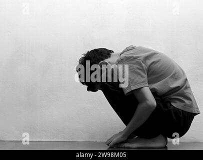 Junge betet in Armut auf dem Boden Stockbild ohne Hilfe allein und ganz allein auf weißem Hintergrund Stockfoto Stockfoto