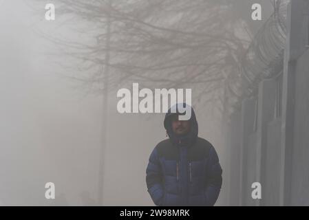 Srinagar, Indien. Dezember 2023. Ein Mann läuft bei dichtem Nebel auf einer Straße in Srinagar. Intensive Kälte gepaart mit dichtem Nebel und Dunst störte das normale Leben im Kaschmir-Tal am Montag. Srinagar und andere Teile des Kaschmir-Tals waren von einer dicken Schicht Nebel und Dunst umgeben, die die Sicht einschränkte und Pendlern Unannehmlichkeiten bereitete. (Foto: Idrees Abbas/SOPA Images/SIPA USA) Credit: SIPA USA/Alamy Live News Stockfoto