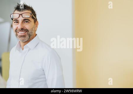 Ein Portraitfoto eines Geschäftsmannes mittleren Alters, der im Büro steht und lächelt, während er in die Kamera schaut. Kopierbereich. Stockfoto