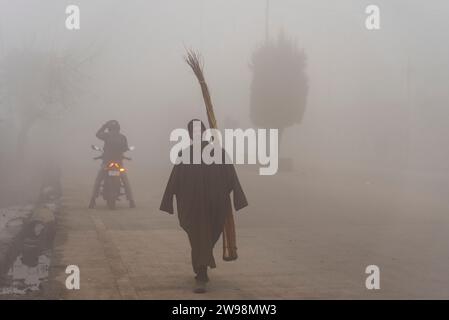 Srinagar, Indien. Dezember 2023. Ein Mann läuft bei dichtem Nebel auf einer Straße in Srinagar. Intensive Kälte gepaart mit dichtem Nebel und Dunst störte das normale Leben im Kaschmir-Tal am Montag. Srinagar und andere Teile des Kaschmir-Tals waren von einer dicken Schicht Nebel und Dunst umgeben, die die Sicht einschränkte und Pendlern Unannehmlichkeiten bereitete. (Foto: Idrees Abbas/SOPA Images/SIPA USA) Credit: SIPA USA/Alamy Live News Stockfoto