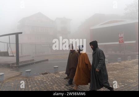 Srinagar, Indien. Dezember 2023. Die Menschen laufen in Srinagar bei dichtem Nebel auf einer Straße entlang. Intensive Kälte gepaart mit dichtem Nebel und Dunst störte das normale Leben im Kaschmir-Tal am Montag. Srinagar und andere Teile des Kaschmir-Tals waren von einer dicken Schicht Nebel und Dunst umgeben, die die Sicht einschränkte und Pendlern Unannehmlichkeiten bereitete. (Foto: Idrees Abbas/SOPA Images/SIPA USA) Credit: SIPA USA/Alamy Live News Stockfoto