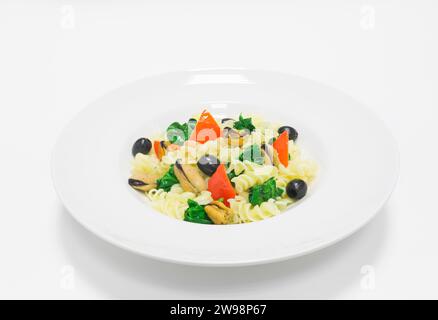 Gourmet-Pasta mit Muscheln, Basilikum und Oliven. Draufsicht. Weißer Hintergrund. Konzept für gesunde Ernährung. Gemischte Medien Stockfoto