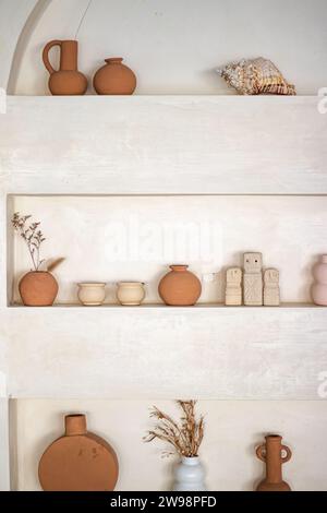 Eine Auswahl an verschiedenen Tontöpfen und anderen Artefakten auf Regalen im mediterranen Stil Stockfoto